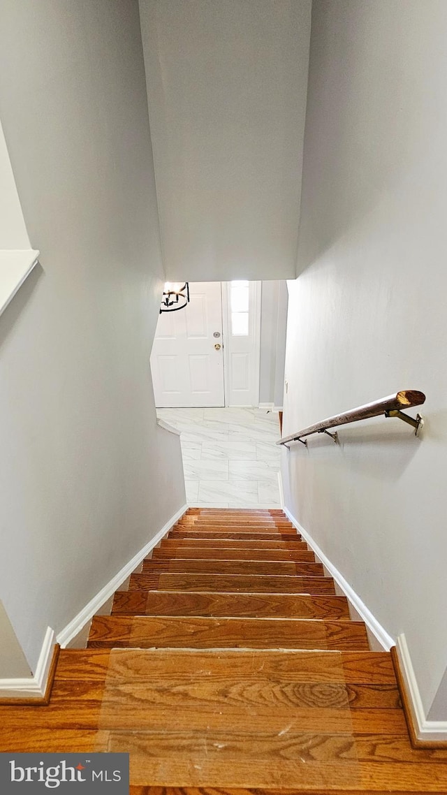 staircase featuring baseboards and wood finished floors