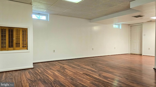 basement featuring baseboards, visible vents, a drop ceiling, and wood finished floors