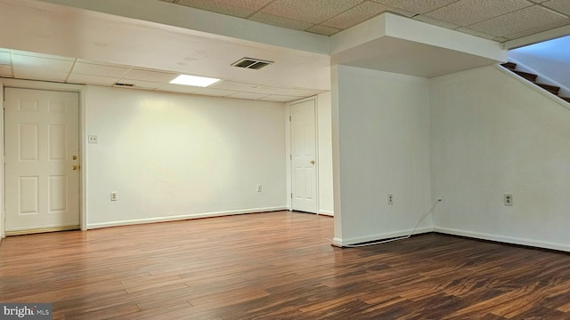 unfurnished room featuring baseboards, visible vents, a paneled ceiling, and wood finished floors