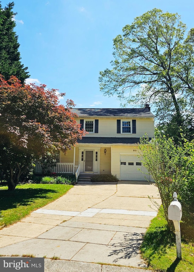 traditional home with covered porch, driveway, a chimney, a garage, and a front lawn