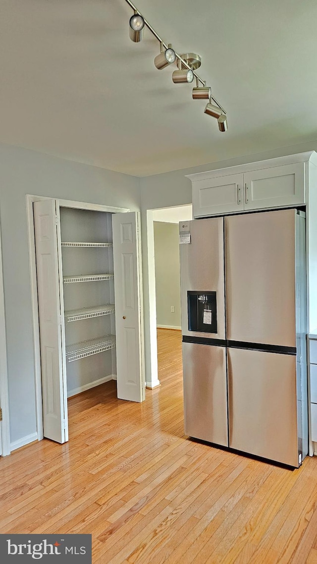 kitchen featuring white cabinets, baseboards, light wood-style flooring, and stainless steel fridge with ice dispenser