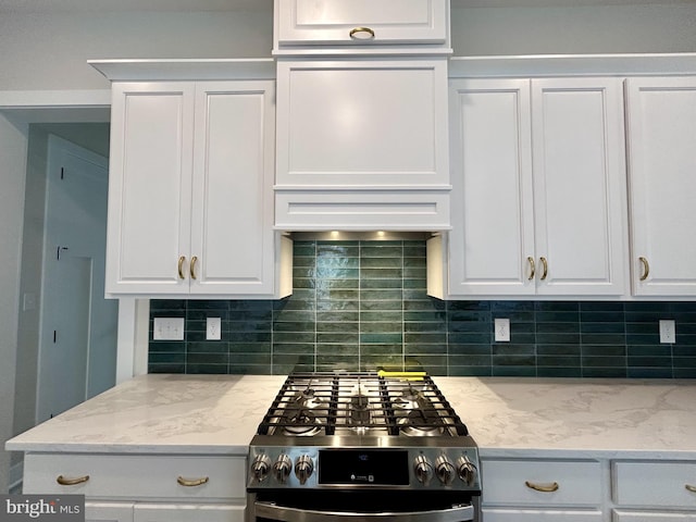 kitchen with gas stove, white cabinets, and backsplash