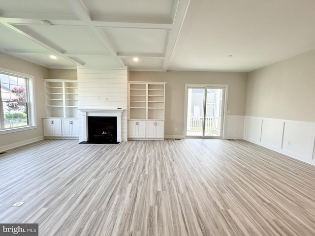 unfurnished living room featuring coffered ceiling, a large fireplace, beam ceiling, and light wood-style floors