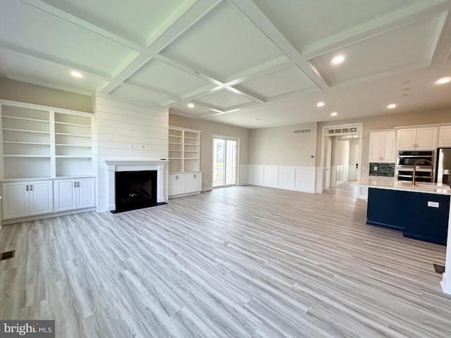unfurnished living room featuring a large fireplace, light wood-style flooring, recessed lighting, visible vents, and coffered ceiling