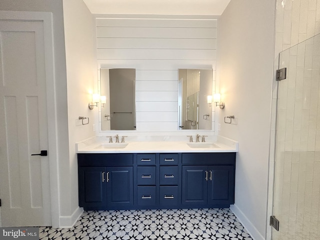 full bath featuring double vanity, a sink, a stall shower, and tile patterned floors