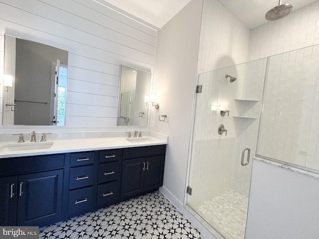 full bathroom featuring double vanity, a sink, tile patterned floors, and a shower stall