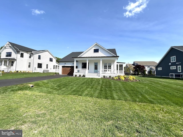 neoclassical home with a porch, a garage, driveway, and a front yard