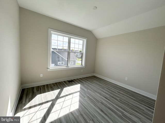 empty room featuring baseboards, dark wood finished floors, and lofted ceiling