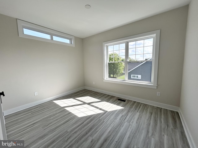 spare room featuring baseboards, wood finished floors, and visible vents