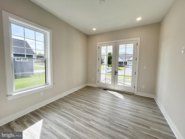 unfurnished room with light wood-style floors, baseboards, and french doors