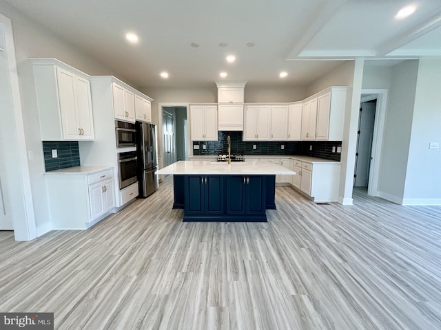 kitchen featuring white cabinets, backsplash, appliances with stainless steel finishes, and light countertops