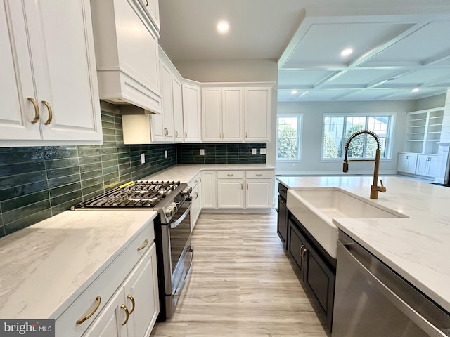 kitchen featuring appliances with stainless steel finishes, a sink, white cabinets, custom exhaust hood, and recessed lighting