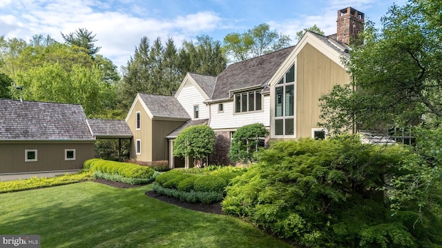 rear view of property featuring a lawn and a chimney