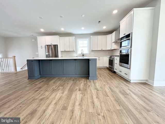kitchen with light countertops, stainless steel appliances, light wood-style flooring, and white cabinetry