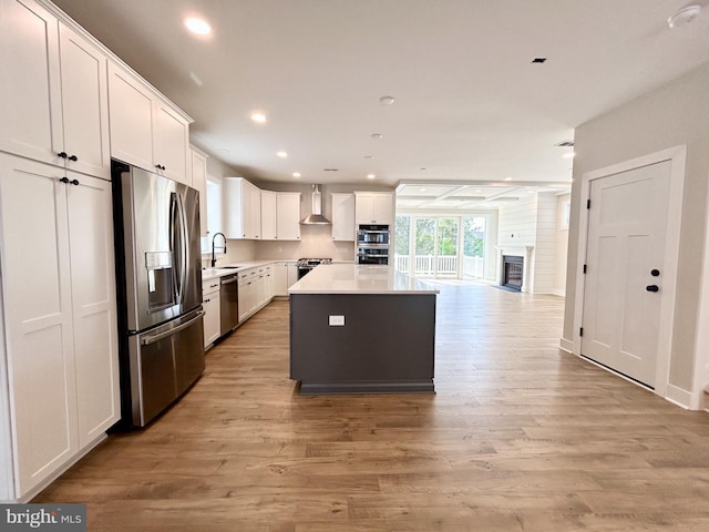 kitchen featuring light wood-style floors, open floor plan, a center island, white cabinets, and stainless steel appliances