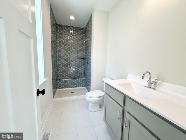 bathroom featuring toilet, visible vents, tiled shower, and tile patterned flooring