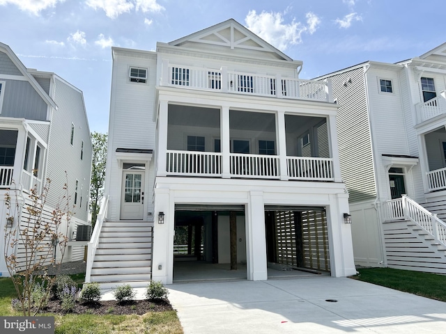 raised beach house with a garage, stairway, and concrete driveway