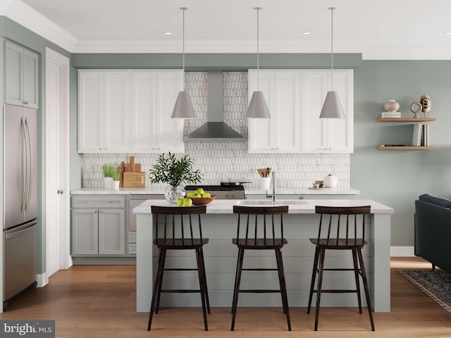 kitchen with stainless steel fridge, light countertops, wall chimney exhaust hood, a sink, and backsplash
