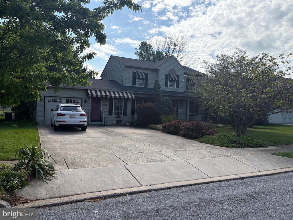 view of front of house featuring concrete driveway, a front yard, and a garage