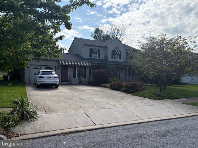 view of front of house featuring concrete driveway, a front yard, and a garage