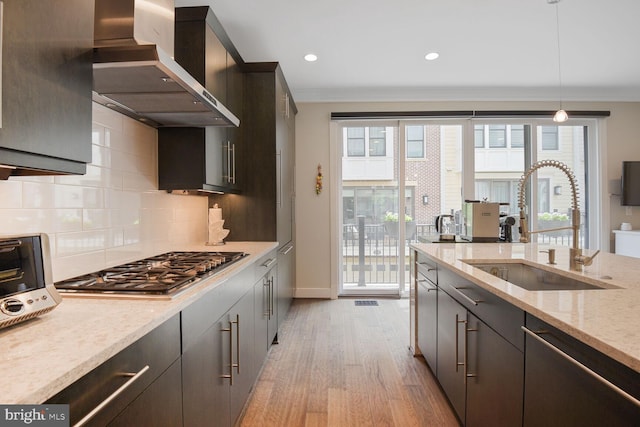 1516 16th Ct N, Arlington, VA 22209 - kitchen with wall chimney range hood, appliances with stainless steel finishes, a sink, light wood-style flooring, and backsplash