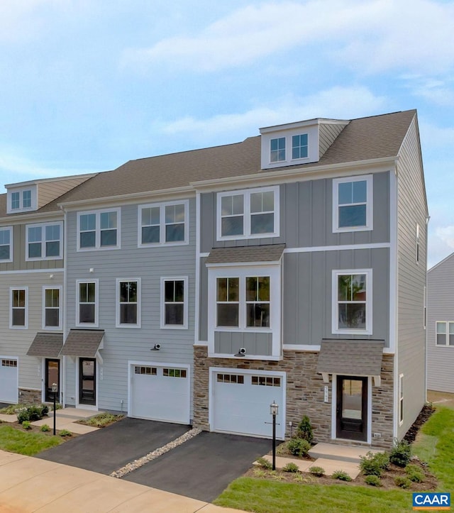 multi unit property featuring a garage, board and batten siding, driveway, and stone siding