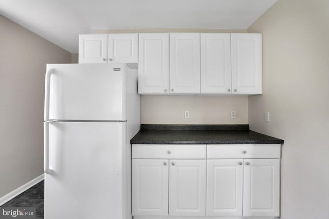 128 Fox Dr, Winchester, VA 22601 - kitchen with freestanding refrigerator, dark countertops, white cabinetry, and baseboards