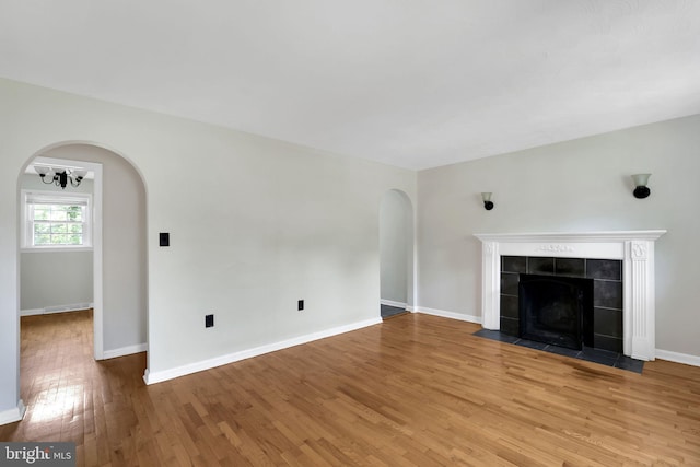 128 Fox Dr, Winchester, VA 22601 - unfurnished living room with wood finished floors, arched walkways, a tile fireplace, and baseboards