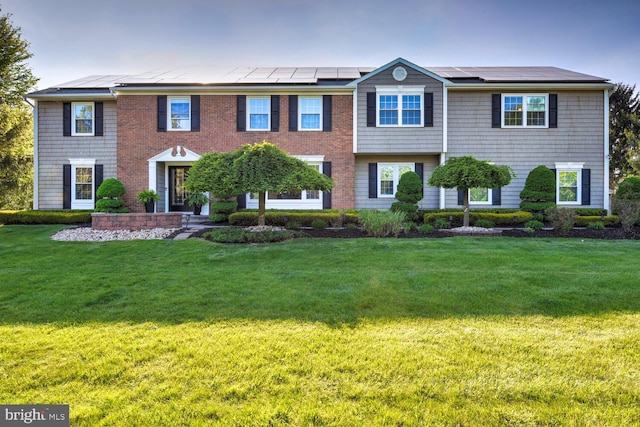 view of front of property with roof mounted solar panels and a front lawn