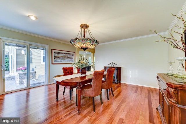dining area with light wood-style flooring, crown molding, and baseboards
