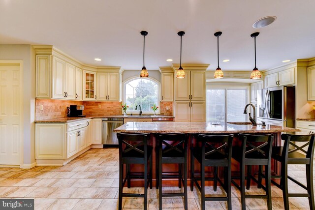 kitchen with cream cabinetry, stainless steel appliances, light stone countertops, a kitchen breakfast bar, and recessed lighting