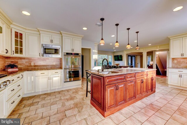 kitchen with appliances with stainless steel finishes, tasteful backsplash, a sink, glass insert cabinets, and light stone counters