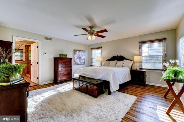 bedroom with baseboards, wood finished floors, ceiling fan, and ensuite bathroom
