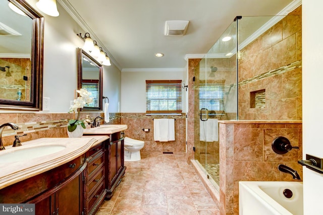 full bath with tile walls, a stall shower, crown molding, two vanities, and a tub to relax in