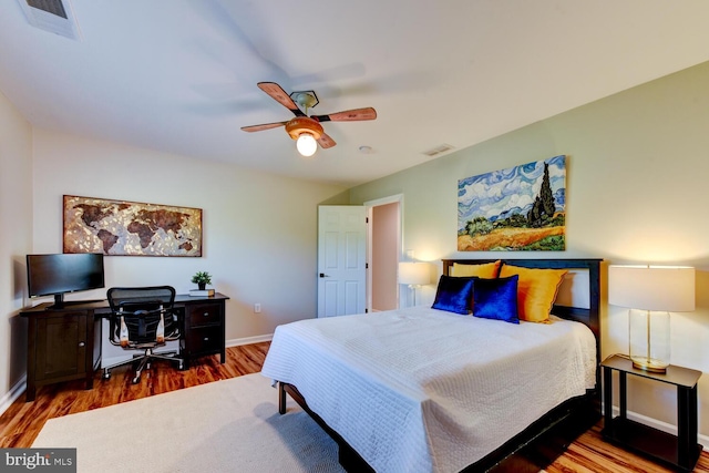 bedroom featuring wood finished floors, baseboards, ceiling fan, and an office area