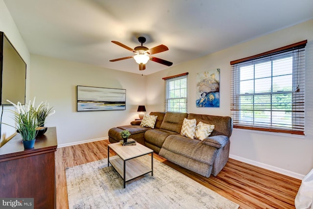 living area featuring wood finished floors, baseboards, and ceiling fan