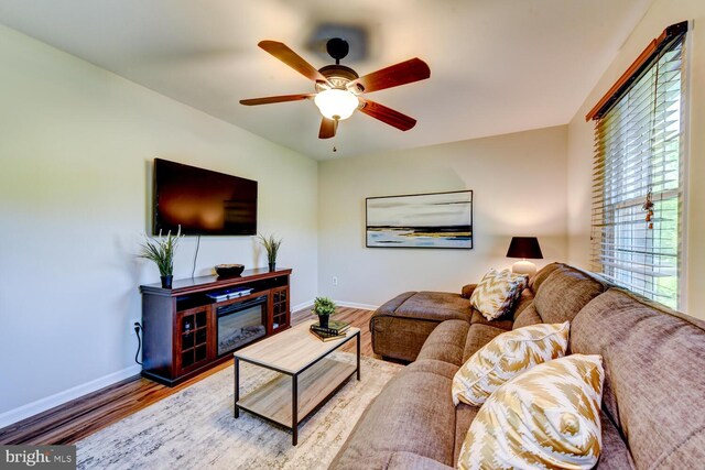 living room with baseboards, wood finished floors, and a ceiling fan