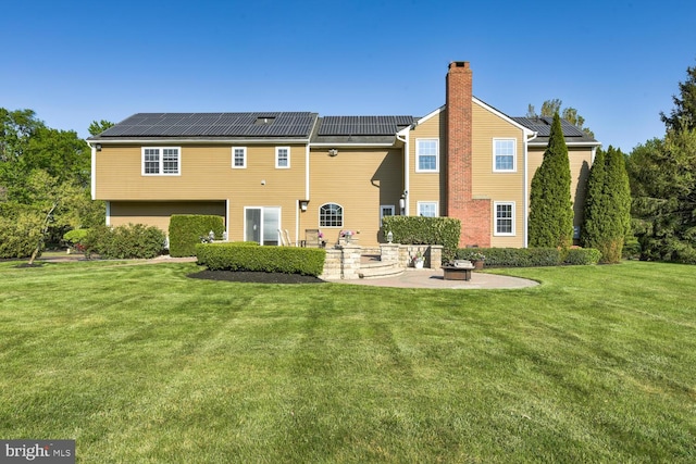 rear view of property with a patio, solar panels, and a yard