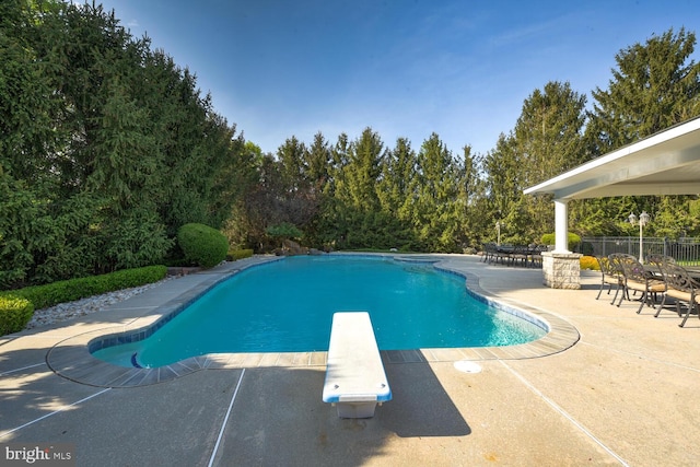 view of pool featuring a patio, fence, and a diving board