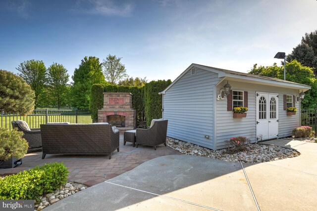view of patio with an outdoor living space with a fireplace, fence, and an outdoor structure
