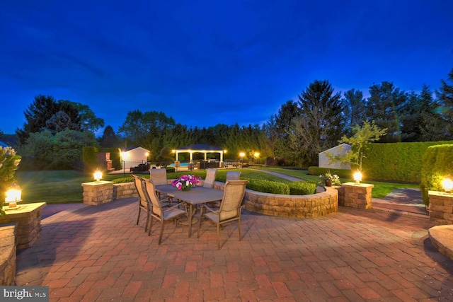 patio at twilight with an outdoor fire pit, a gazebo, and outdoor dining space