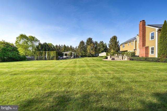 view of green lawn featuring a patio, a shed, and an outbuilding