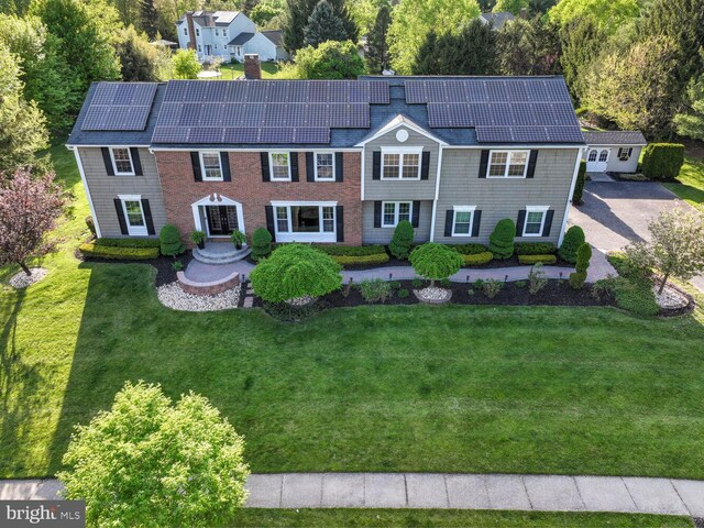 view of front of home with solar panels and a front yard