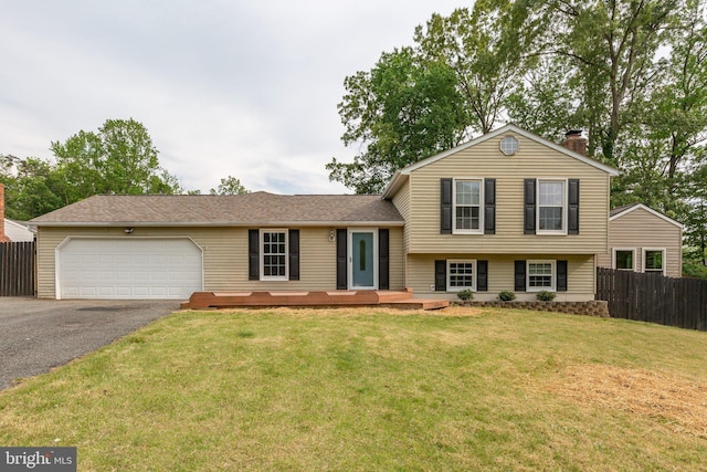 split level home featuring fence, a front lawn, a garage, a chimney, and driveway