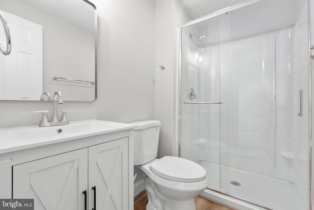 bathroom featuring vanity, wood finished floors, toilet, and a shower stall