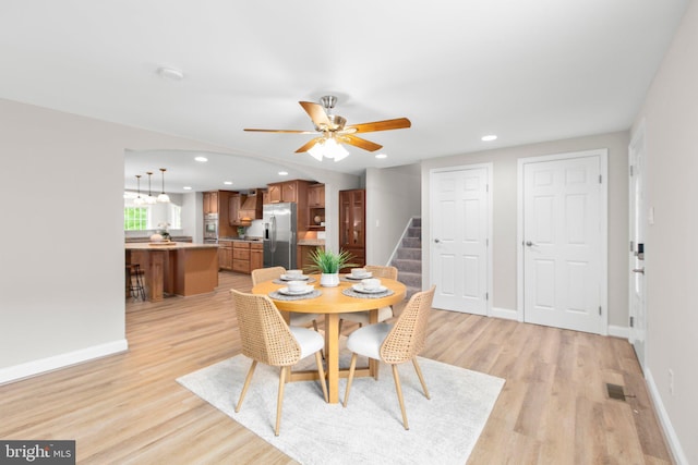 dining room featuring stairs, ceiling fan, baseboards, and light wood-type flooring