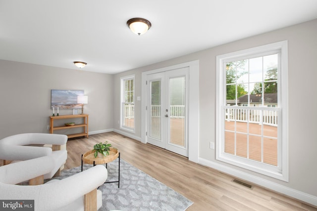 interior space with baseboards, french doors, wood finished floors, and visible vents