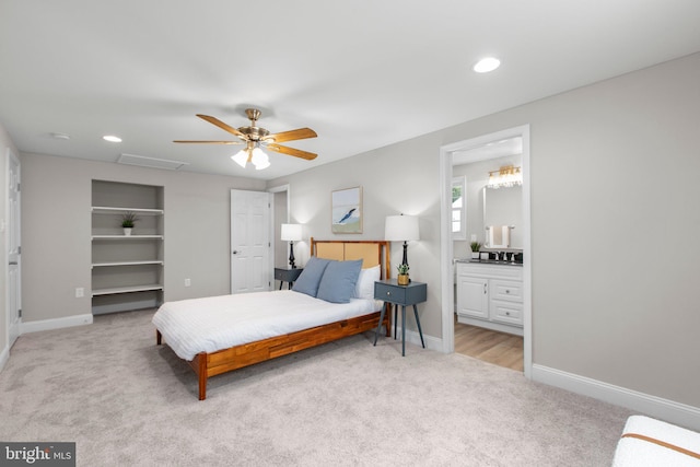bedroom with connected bathroom, light carpet, a walk in closet, recessed lighting, and baseboards