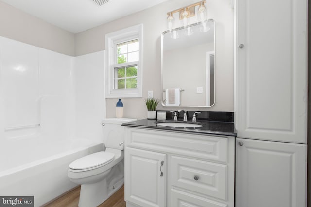 full bath featuring toilet,  shower combination, wood finished floors, and vanity