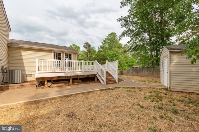 view of yard with fence, a shed, a deck, central AC unit, and an outdoor structure